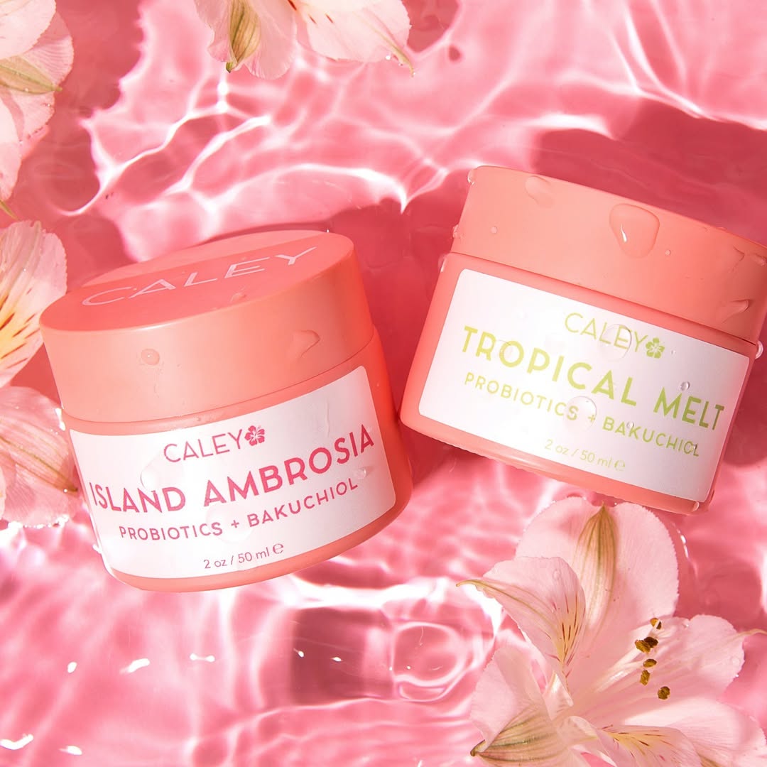 Caley Island Ambrosia Bakuchiol Moisturizer and Tropical Melt Bakuchiol Cleansing Balm displayed on a pink water background.