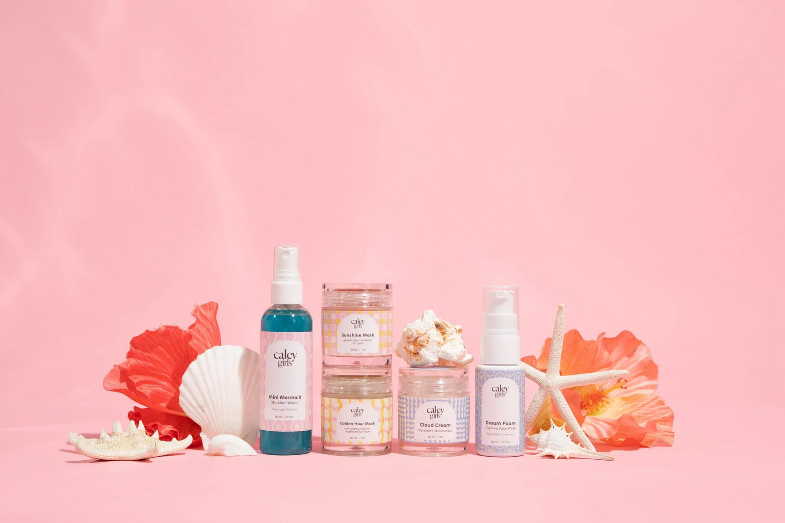 Caley Cosmetics girls' skincare collection with cleanser, moisturizer, micellar water, and skincare products styled with seashells.