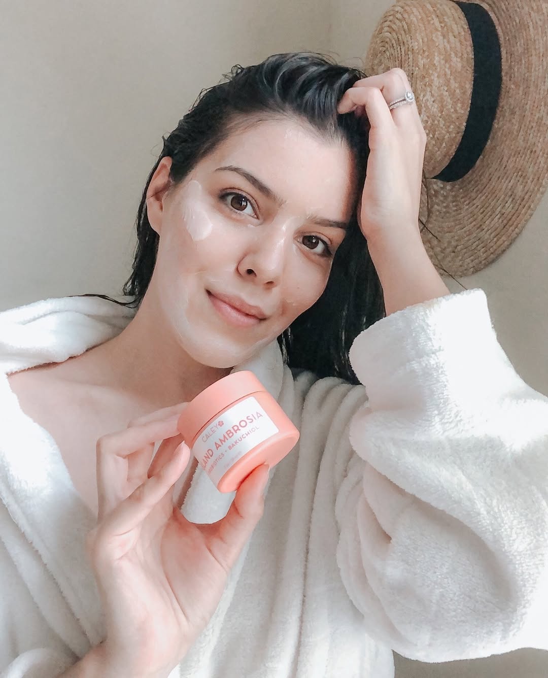 Caley Cosmetics Island Ambrosia moisturizer and Tropical Melt cleansing balm on water with tropical flowers.