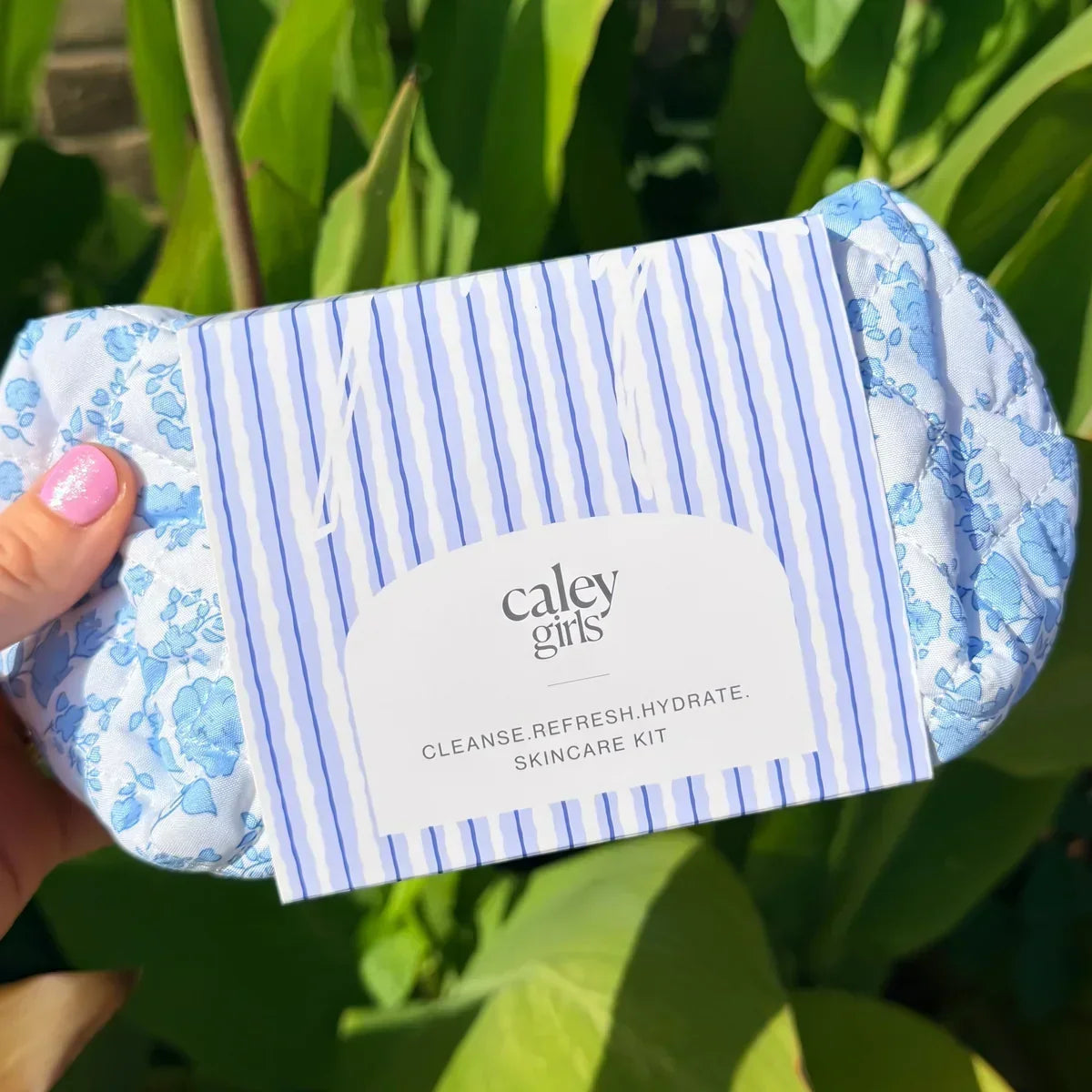 Caley Girls Cleanse.Refresh.Hydrate skincare kit with a blue floral quilted bag in sunlight.