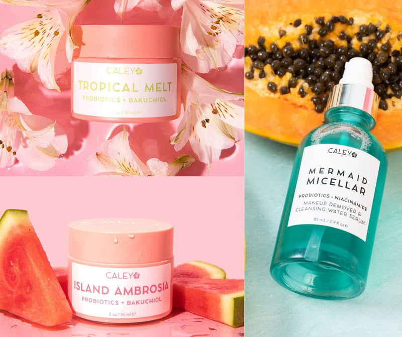 Caley Tropical Melt cleansing balm, Island Ambrosia moisturizer, and Mermaid Micellar cleanser displayed with tropical fruit and colorful flowers.