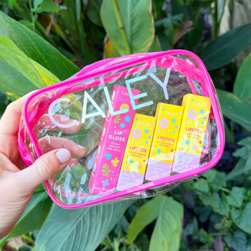Caley Cosmetics kids clean makeup kit held in hand against a green leafy background.