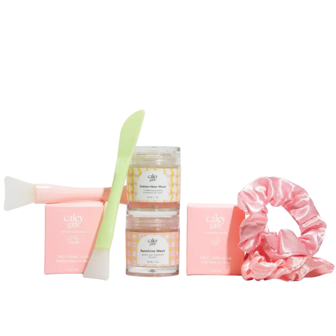 A beauty gift set featuring two small jars of face masks, a gentle kids face mask and a peptide face mask for mom, hair product, two pink boxes, a light green spatula, and a pink satin scrunchie, arranged on a clean white background.